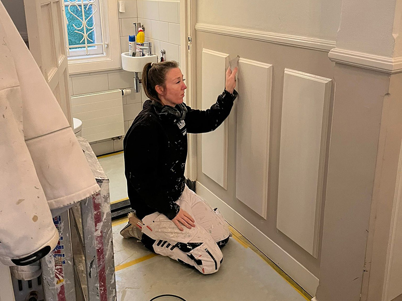 Schilder voert onderhoudswerkzaamheden uit aan kozijnen in de regio Den Haag om schilderwerk te behouden.